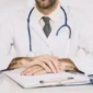 close-up-male-doctor-s-hand-with-clipboard-desk