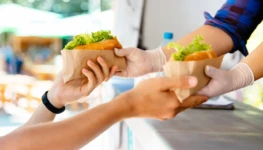 man-buying-two-hot-dog-kiosk-outdoors-street-food-close-up-view-scaled-1