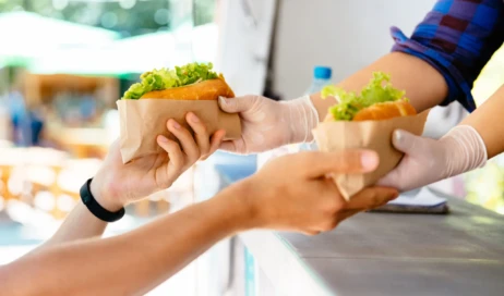 man-buying-two-hot-dog-kiosk-outdoors-street-food-close-up-view-scaled-1