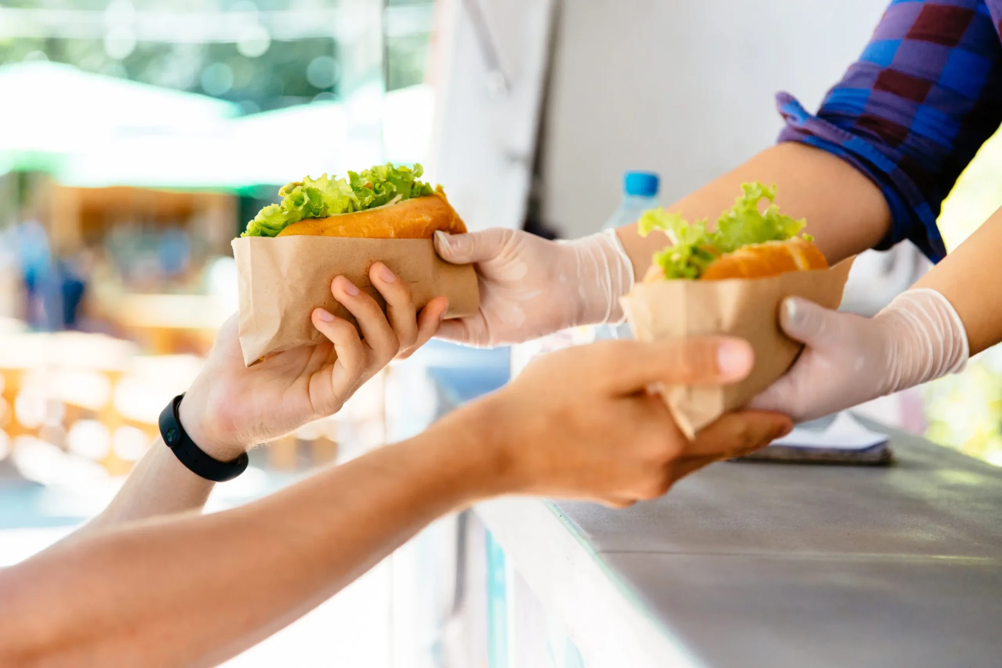 man-buying-two-hot-dog-kiosk-outdoors-street-food-close-up-view-scaled-1